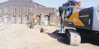 Auf dem Gelände des ehemaligen Bahnausbesserungswerks in Trier-West/Pallien laufen Baggerarbeiten, die den Teilabriss der Lokrichthalle vorbereiten.